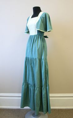 "Description: Vintage 1970s green and cream prairie style maxi dress. Polyester/cotton blend. It has a square neckline, with a lace covered bodice. It has crocheted trim. Short, fluttery sleeves and a ruffled hem. It has attached back ties. Tiered style skirt. Condition: In good condition. No holes. It has a few faint spots. The trim on this dress is very faintly green -- the color bled when it was soaked and attached to the crochet trim. But it is completely even all around, and looks intention Spring Maxi Dress With Lace Trim And Square Neck, Fitted Square Neck Maxi Dress With Lace Trim, Green Maxi Dress With Lace Trim For Spring, Fitted Spring Maxi Dress With Crochet Trim, Fitted Maxi Dress With Crochet Trim For Spring, Cotton Maxi Dress With Lace Trim For Garden Party, Spring Prairie Dress With Lace Trim Maxi Length, Green Bohemian Maxi Dress With Square Neck, Vintage Cotton Maxi Dress With Lace Trim