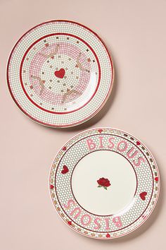 two red and white plates with designs on them sitting next to each other in front of a pink background