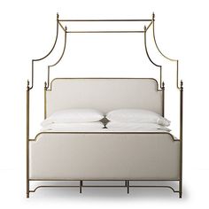 an iron bed frame with two pillows on top of it and white linens in the middle