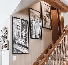 three framed pictures hang on the wall above stairs in a home with wood banisters