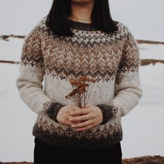 a woman standing in the snow with her hands on her hip and wearing a sweater