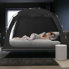 a woman laying on top of a bed next to a table and chair in a room