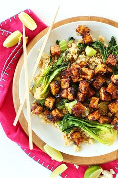 a white plate topped with meat and veggies next to two chopsticks