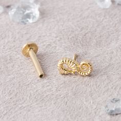 two pairs of gold ear studs sitting on top of a white surface