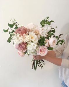 a woman holding a bouquet of white and pink flowers