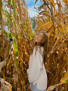 a woman standing in a corn field with her eyes closed