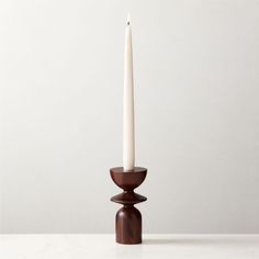 a white candle sitting on top of a wooden stand next to a wall and floor