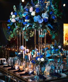 the table is set with blue and white flowers, silver candlesticks, and glassware