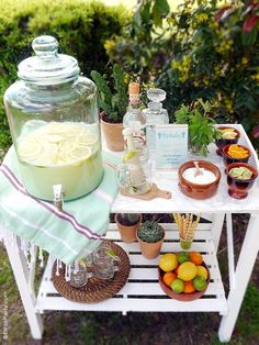 a table topped with potted plants next to a glass jar filled with lemons