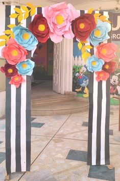 two large paper flowers are on poles in front of a building with columns and pillars