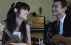 a man and woman sitting next to each other playing guitars