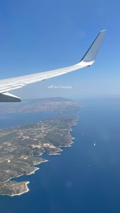 an airplane wing flying over the ocean and land