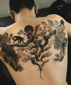 the back of a man's upper half covered in ink with animals and trees