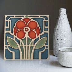 a white vase sitting next to a decorative tile