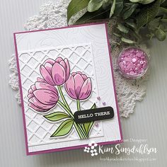 a card with pink flowers on it next to a lace doily and potted plant