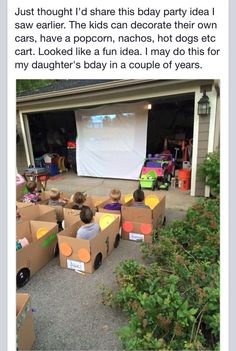 an image of people sitting in cardboard boxes on the ground with a projector screen behind them