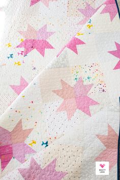 a pink and white quilt with stars on it