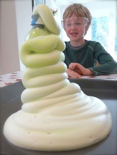 a young boy sitting at a table with a stack of doughnuts in front of him