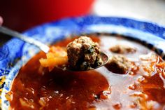 a spoon full of soup with meatballs in it