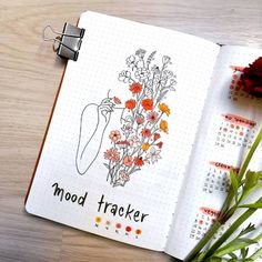 an open notebook with flowers on it and the words mood tracker written in black ink