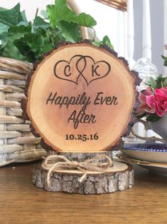 a wood slice with the words happily ever after engraved on it and some flowers in the background