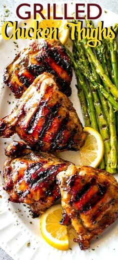 grilled chicken thighs on a plate with asparagus and lemons next to it