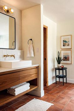 a bathroom with tile flooring and wooden cabinetry in the center, along with a large mirror on the wall