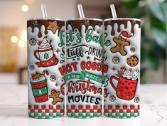 two christmas themed tumblers sitting on top of a counter