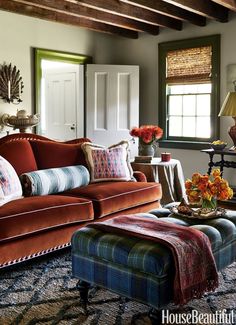 a living room scene with focus on the couch and footstool in the foreground