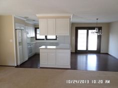 an empty kitchen and living room with sliding glass doors leading to the front door is shown