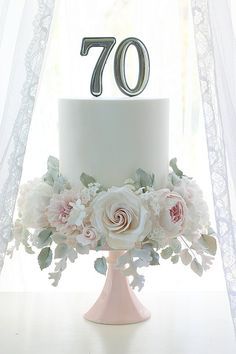 a white cake sitting on top of a table next to a window with sheer curtains