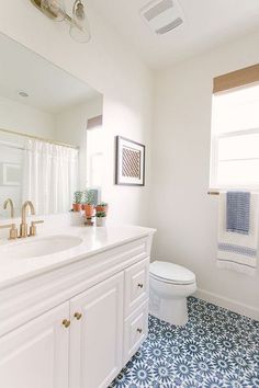 a bathroom with blue and white tile flooring next to a sink, toilet and window