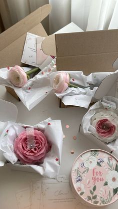 some pink flowers are sitting on a table next to boxes and paper napkins that say i love you