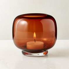 a candle that is inside of a glass vase on a table with a white background