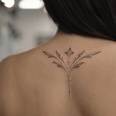 the back of a woman's neck with a flower tattoo on her left shoulder