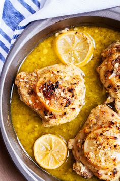 three pieces of chicken in a pan with lemons