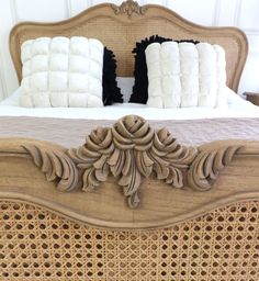 a bed with two pillows on top of it and an ornate headboard in the middle