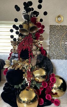 a christmas tree made out of gold and black ornaments in a living room with other decorations on the wall