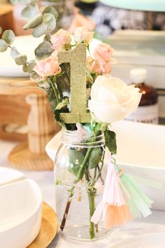 a vase filled with flowers sitting on top of a table next to plates and utensils