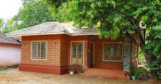 a small brick house sitting under a tree