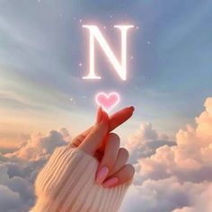 a hand holding up a heart in the sky with the letter n above it and clouds below