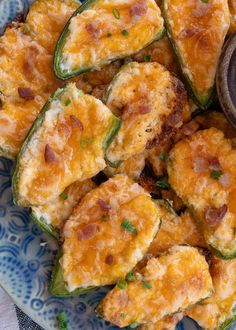 a blue and white plate topped with cheesy stuffed jalapeno peppers