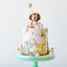 a baby's first birthday cake with an elephant and giraffe topper