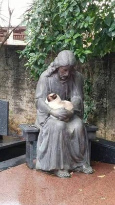 a statue holding a cat sitting on top of a bench