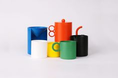 several different colored cups and containers on a white surface with one cup in the middle