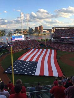 an american flag is being displayed on the field at a baseball game in front of a crowd