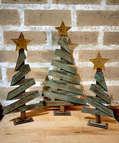 three small wooden christmas trees sitting on top of a table next to a brick wall