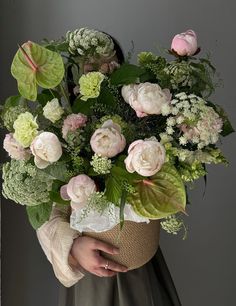 a woman holding a bouquet of flowers in her hands with greenery on the side