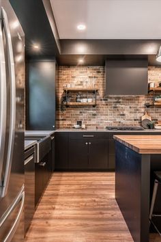 a kitchen with wooden floors and black cabinets, stainless steel appliances and countertop space