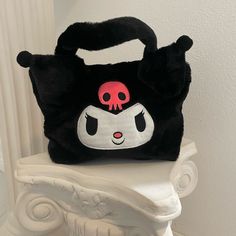 a black and white cat purse sitting on top of a white chair next to a wall